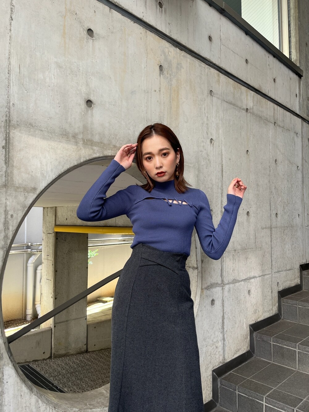 ブルー系のニット/セーター、ブラック系のスカート、ホワイト系のブーツを着用したレディースの秋コーディネートの2枚目の写真