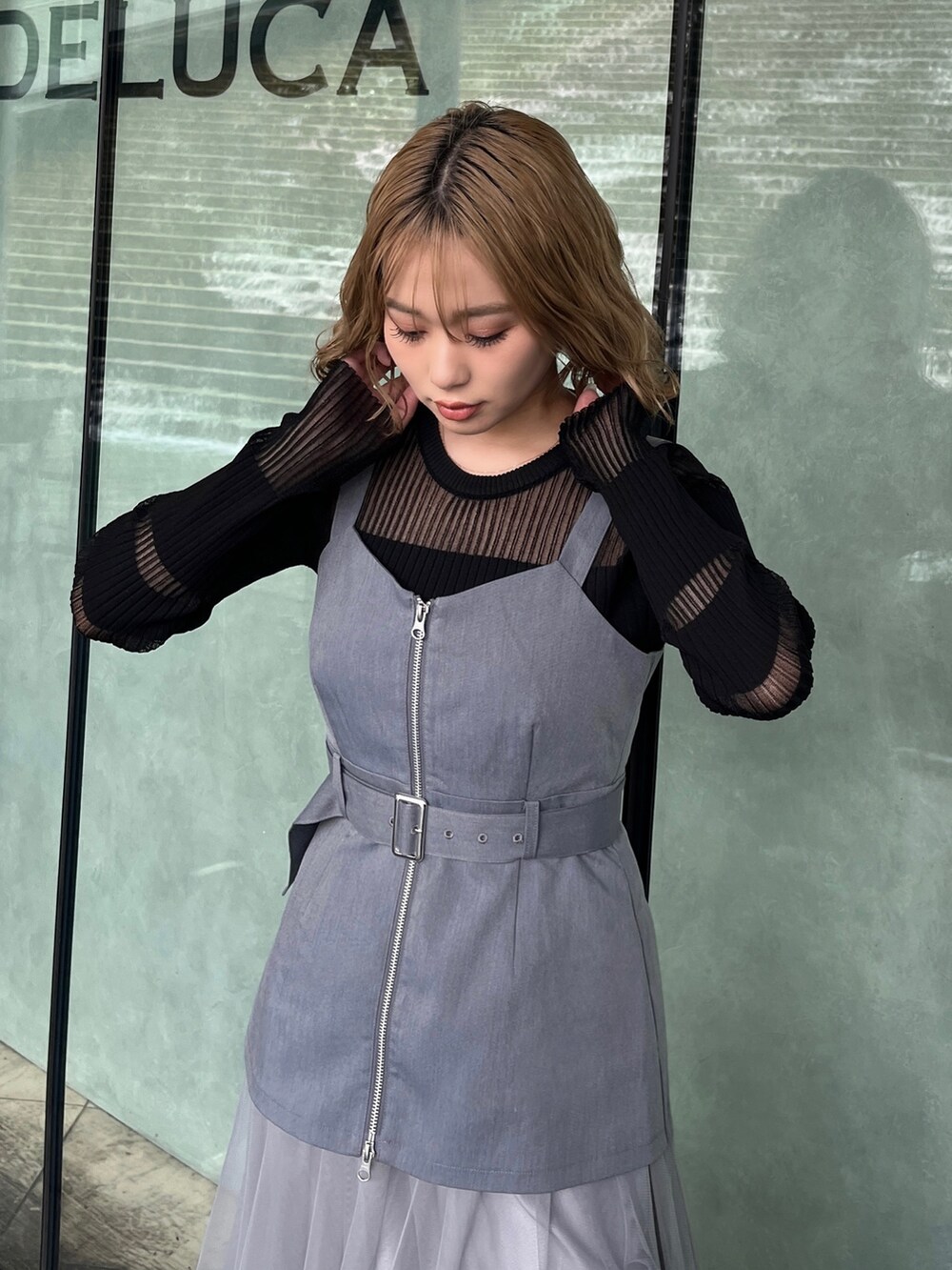 ブラック系のニット/セーター、グレー系のジャンパースカート、ブラック系のブーツを着用したレディースの春コーディネートの3枚目の写真