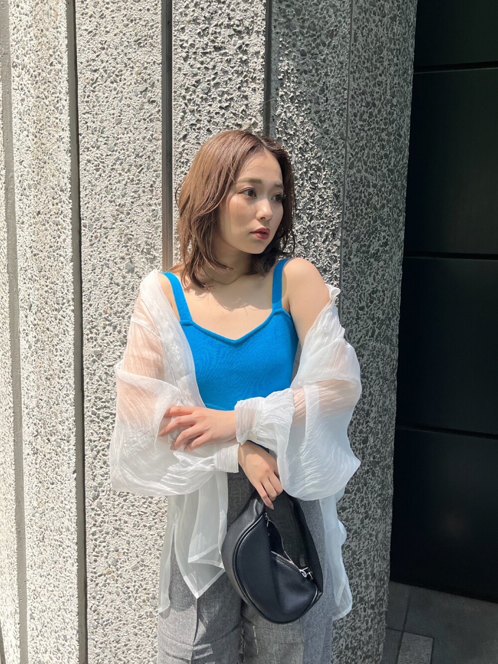 ホワイト系のシャツ/ブラウス、ブルー系のニット/セーター、ブラック系のハンドバッグを着用したレディースの春コーディネートの4枚目の写真