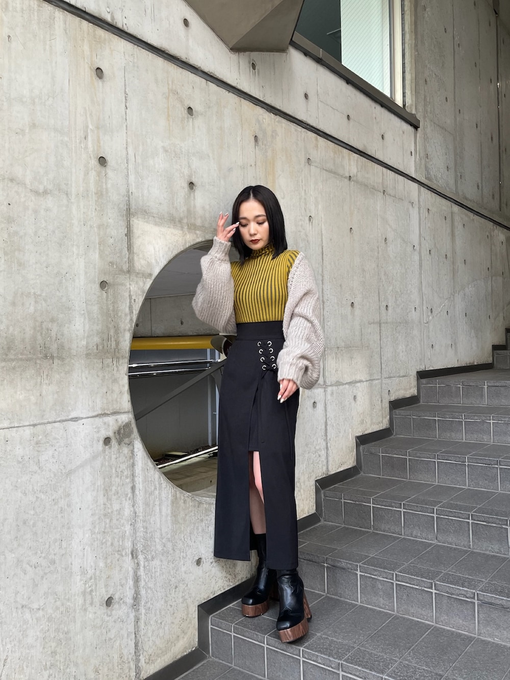 ベージュ系のトレンチコート、イエロー系のニット/セーター、ブラック系のスカートを着用したレディースの夏コーディネートの8枚目の写真
