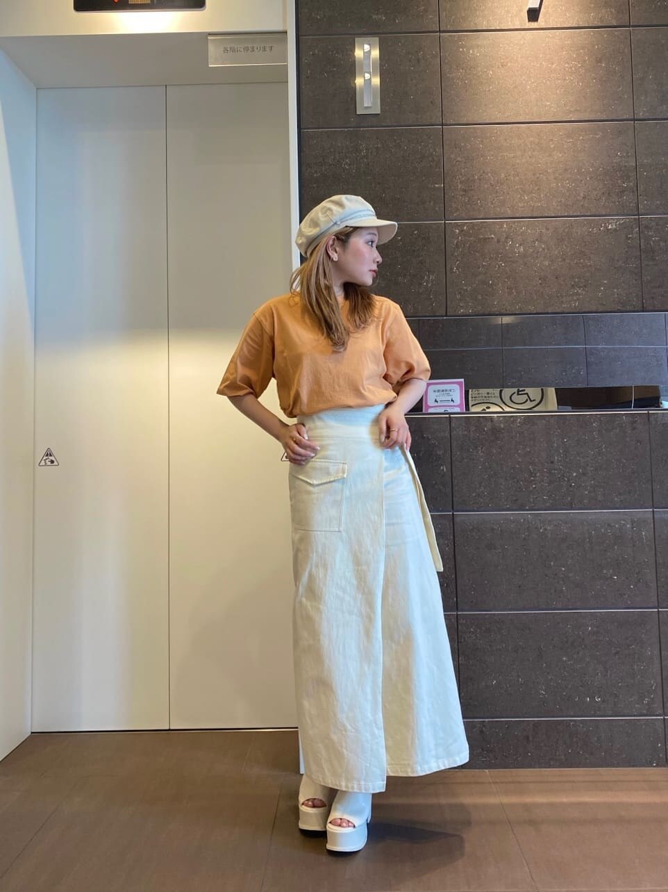 ホワイト系のスカート、オレンジ系のTシャツ/カットソー、ホワイト系のサンダルを着用したレディースの春コーディネートの2枚目の写真