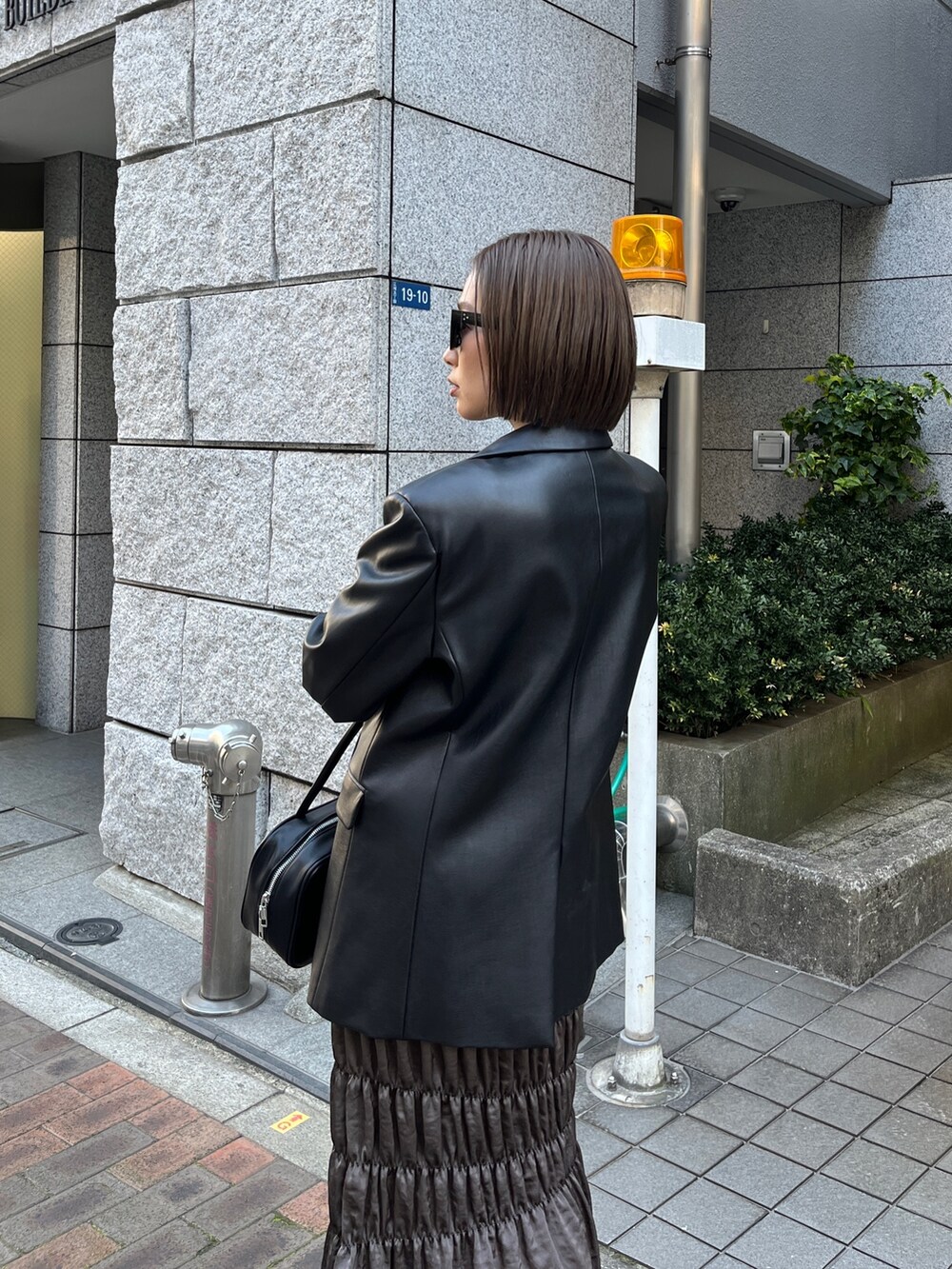 ブラック系のテーラードジャケット、ブラック系のニット/セーター、ブラウン系のスカートを着用したレディースの春コーディネートの5枚目の写真