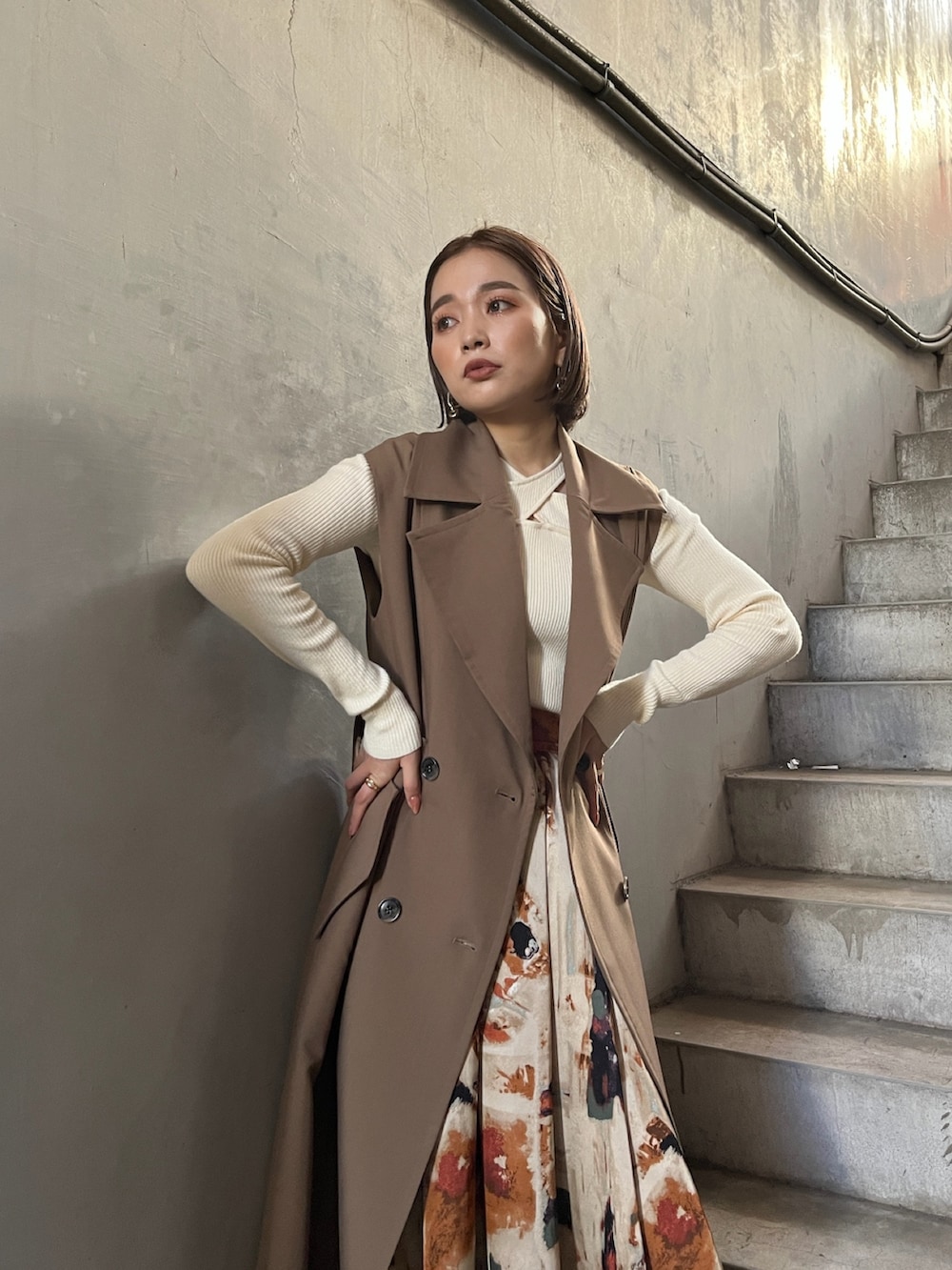 イエロー系のトレンチコート、ホワイト系のニット/セーター、オレンジ系のスカートを着用したレディースの秋コーディネートの5枚目の写真