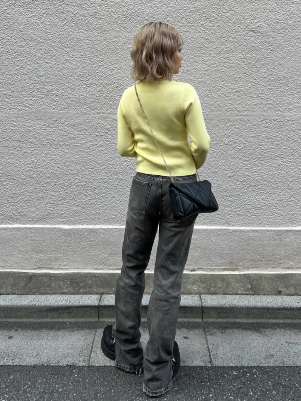 ブラック系のブーツ、イエロー系のニット/セーターを着用したレディースの春コーディネートの3枚目の写真