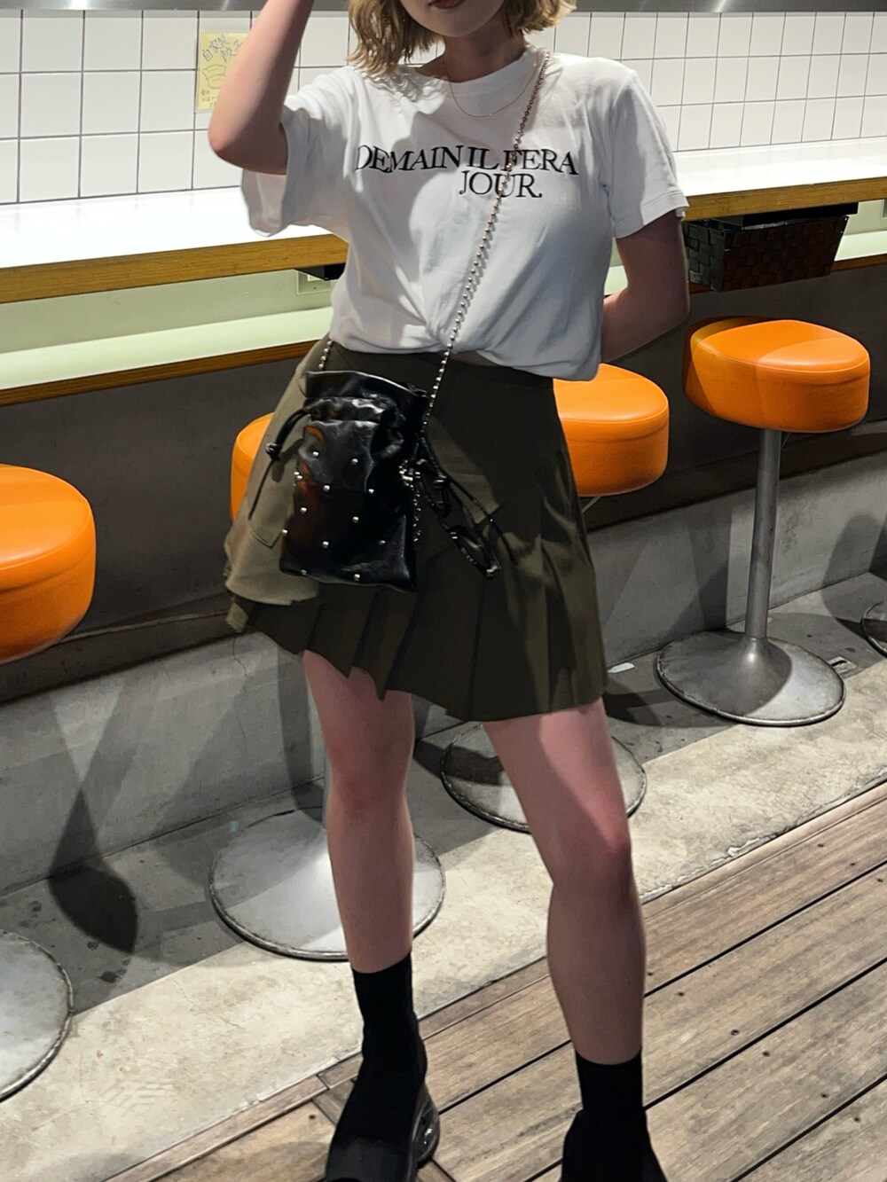 ブラック系のショルダーバッグ、グリーン系のスカートを着用したレディースの夏コーディネートの4枚目の写真