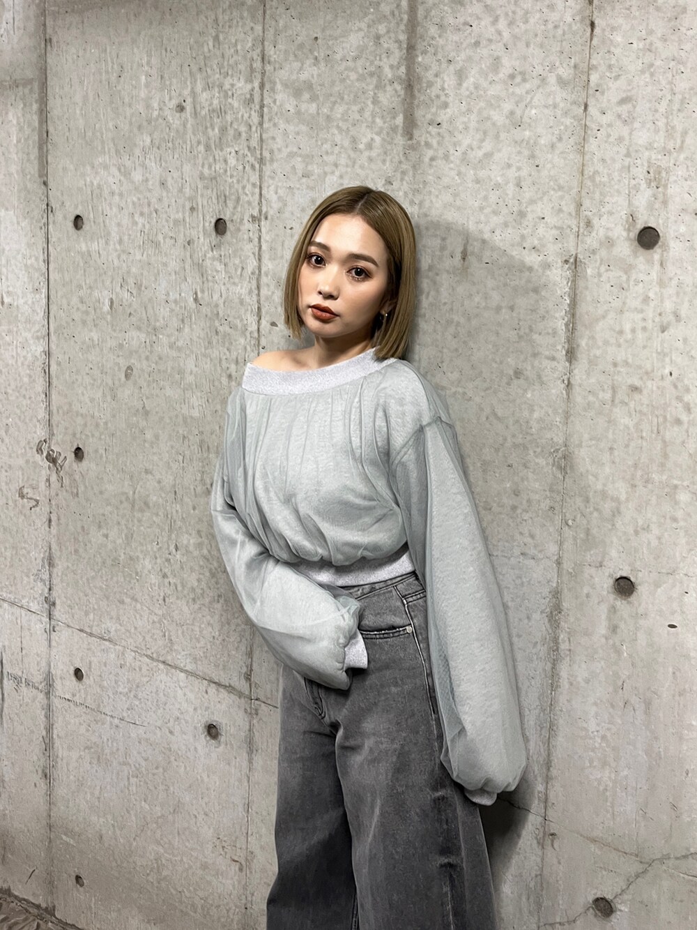 グレー系のスウェット、ブラック系のデニムパンツ、シルバー系のパンプスを着用したレディースの冬コーディネートの7枚目の写真