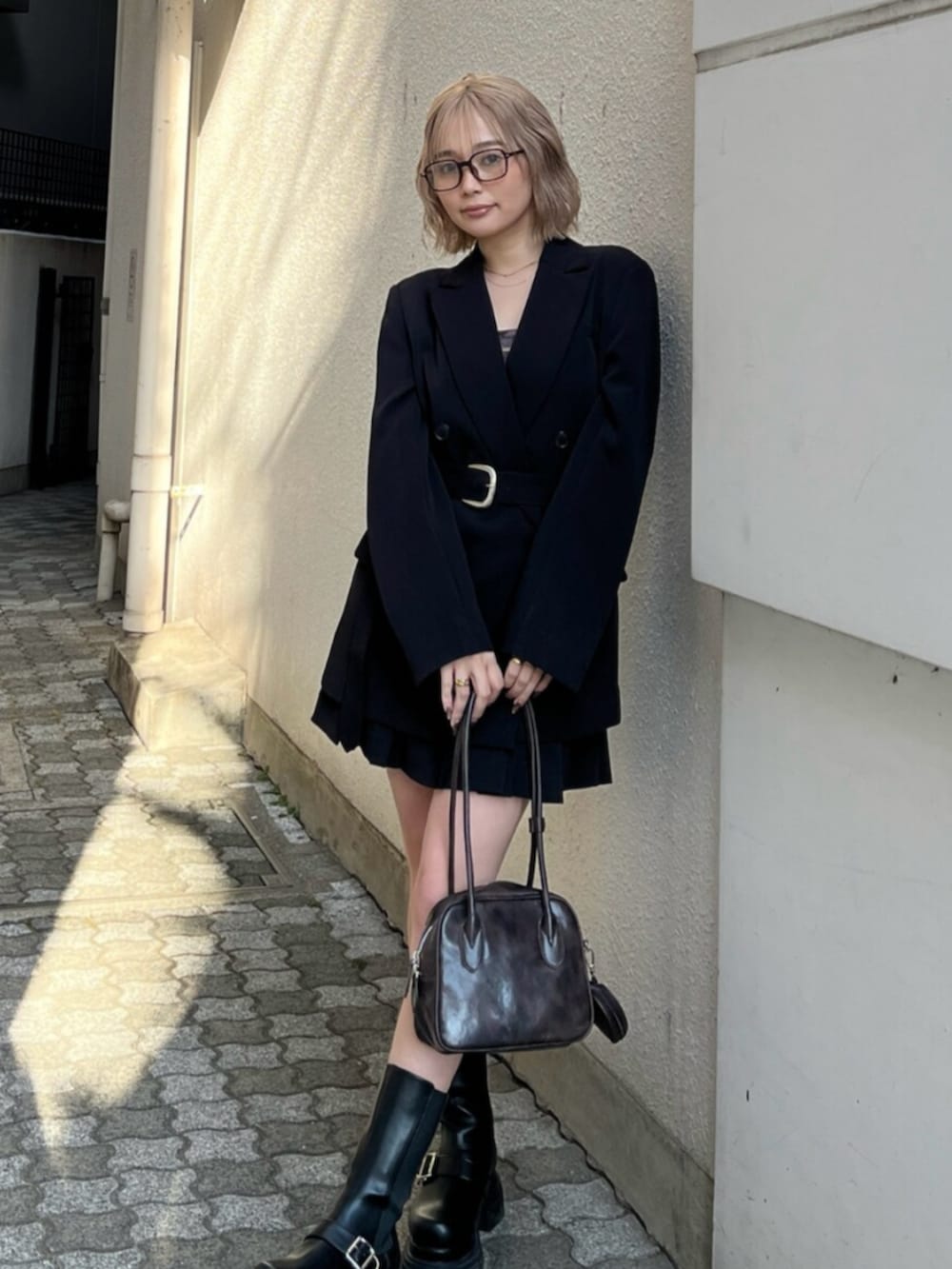 ブラック系のブーツ、ブラック系のテーラードジャケット、ブラウン系のキャミソールを着用したレディースの春コーディネートの2枚目の写真