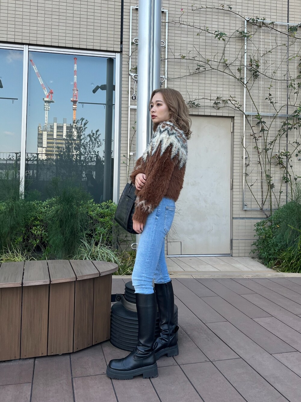 ブラウン系のニット/セーター、ブラック系のブーツを着用したレディースの冬コーディネートの2枚目の写真