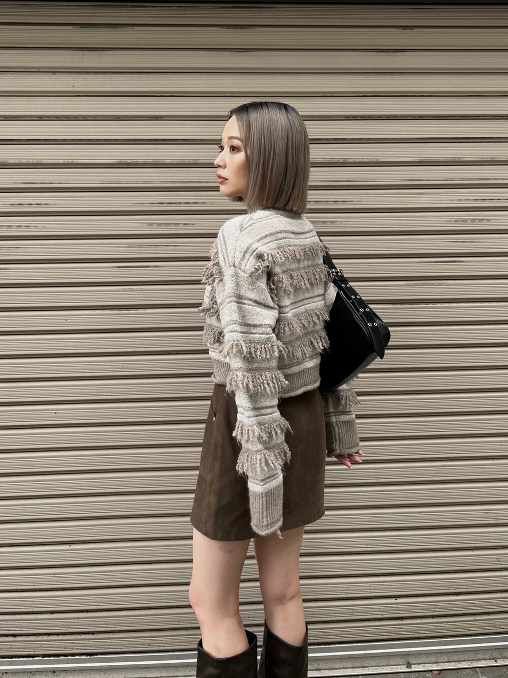 ホワイト系のニット/セーター、ブラック系のハンドバッグ、ブラウン系のスカートを着用したレディースの秋コーディネートの4枚目の写真