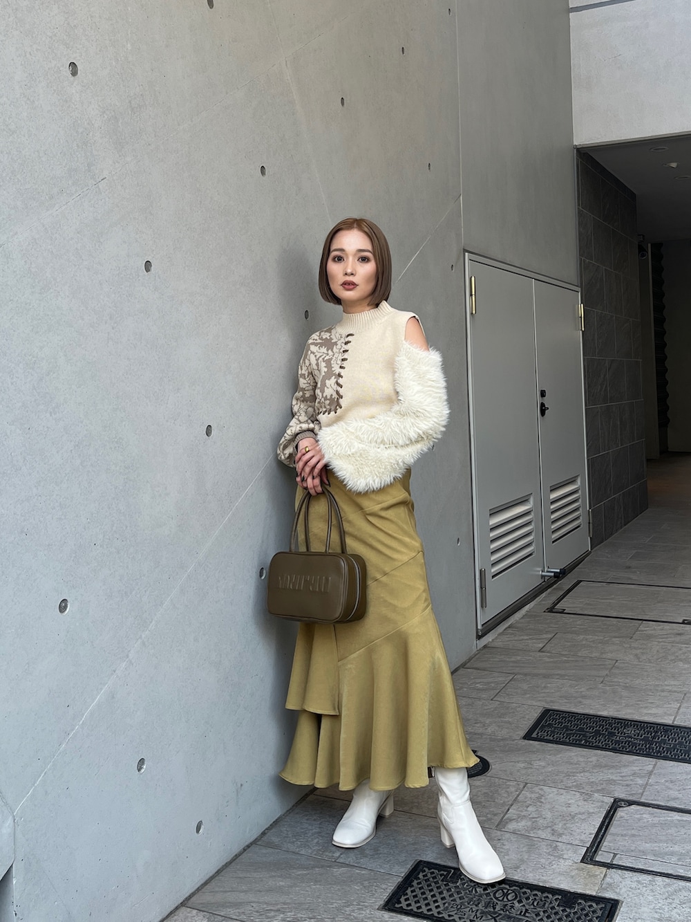 ホワイト系のニット/セーター、イエロー系のボストンバッグ、ホワイト系のブーツを着用したレディースの秋コーディネートの3枚目の写真