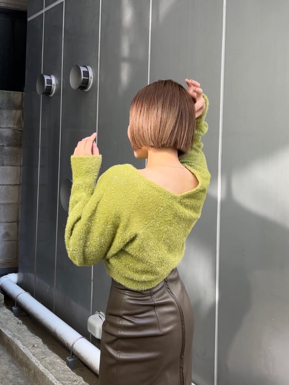 グリーン系のニット/セーター、ブラウン系のスカート、ホワイト系のブーツを着用したレディースの冬コーディネートの2枚目の写真