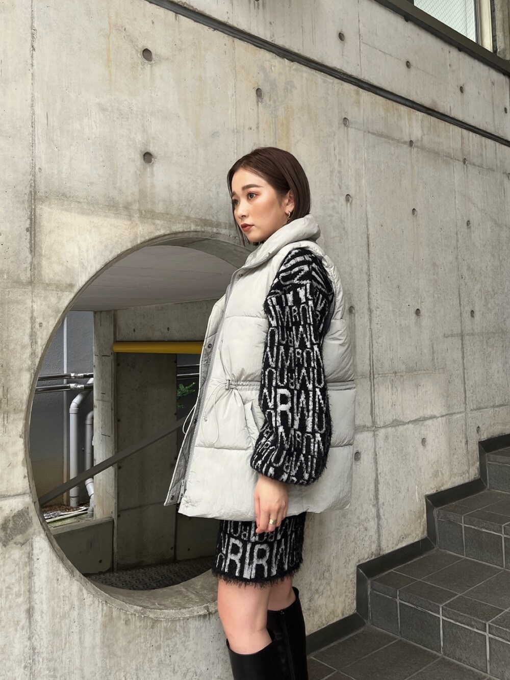 グレー系のダウンベスト、ブラック系のニット/セーター、ブラック系のスカートを着用したレディースの秋コーディネートの3枚目の写真