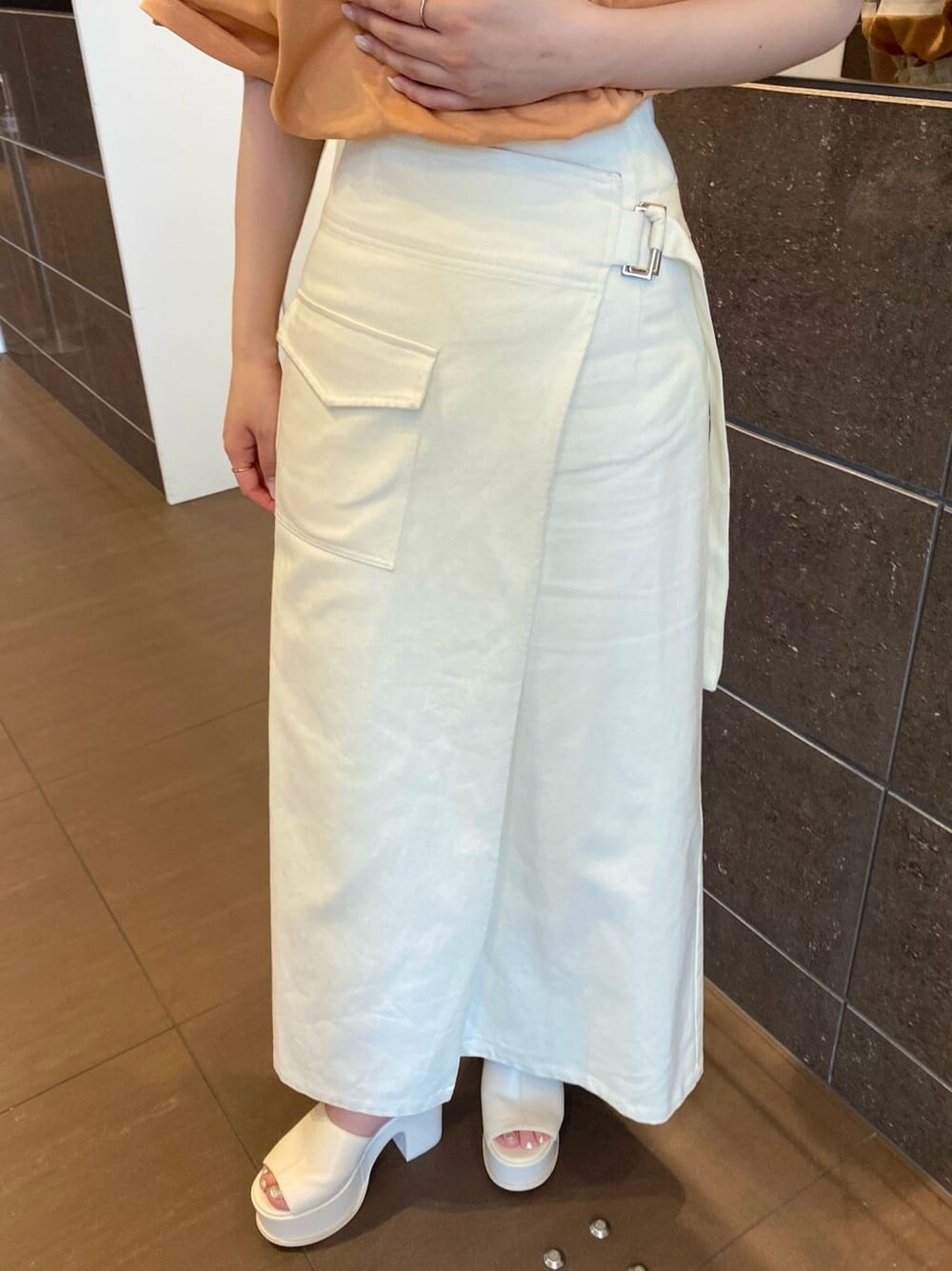 ホワイト系のスカート、オレンジ系のTシャツ/カットソー、ホワイト系のサンダルを着用したレディースの春コーディネートの8枚目の写真