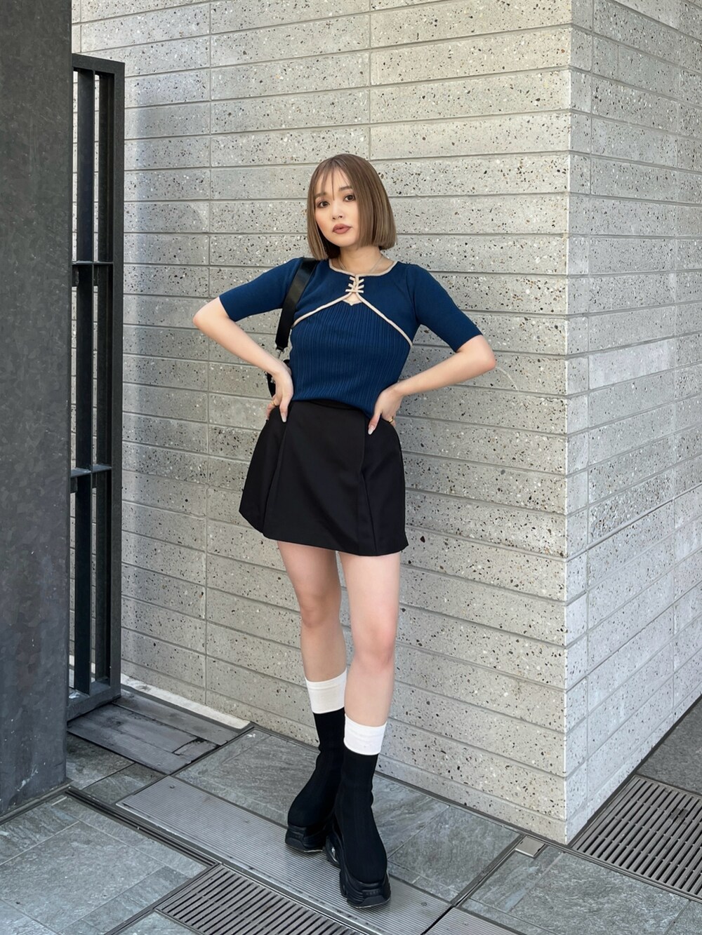 ブラック系のブーツ、ブラック系のスカート、ブルー系のニット/セーターを着用したレディースの春コーディネートの2枚目の写真