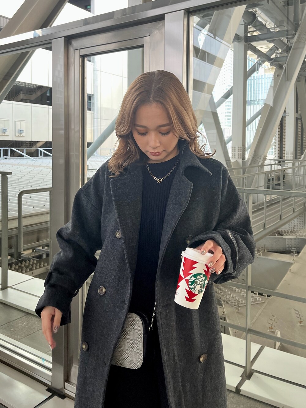 ブラック系のステンカラーコート、ブルー系のニット/セーター、ブラック系のローファーを着用したレディースの冬コーディネートの6枚目の写真