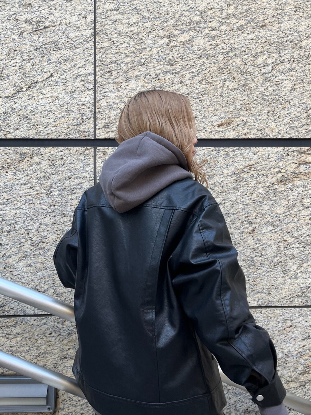 ブラック系のライダースジャケット、グレー系のパーカー、ブラック系のブーツを着用したレディースの秋コーディネートの7枚目の写真
