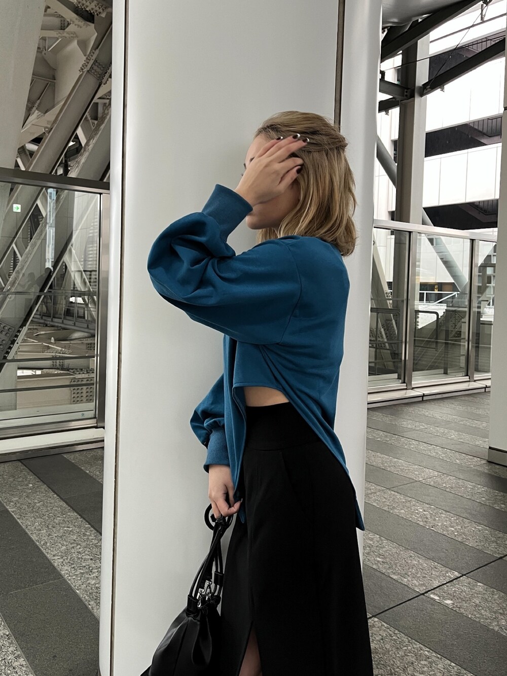 ブルー系のTシャツ/カットソー、ブラック系のスカート、ブラック系のハンドバッグを着用したレディースの冬コーディネートの7枚目の写真