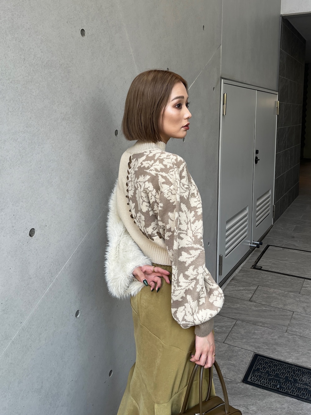 ホワイト系のニット/セーター、イエロー系のボストンバッグ、ホワイト系のブーツを着用したレディースの秋コーディネートの7枚目の写真