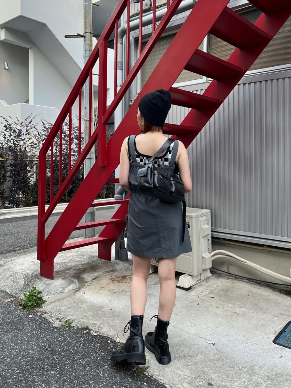 グレー系のワンピース、ブラック系のブーツ、ブラック系のタンクトップを着用したレディースの春コーディネートの2枚目の写真