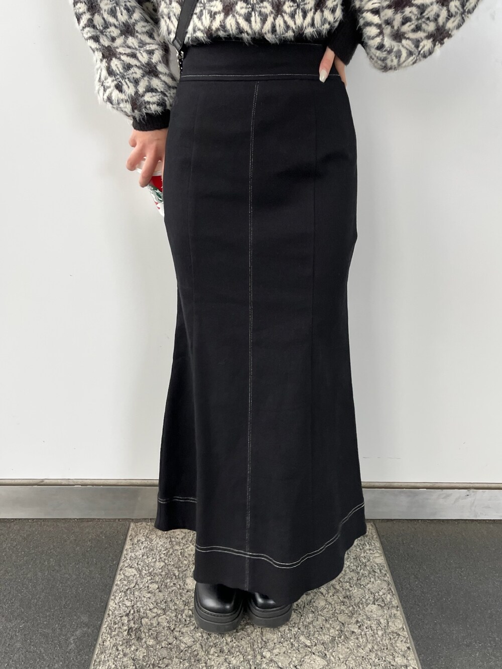 ブラック系のニット/セーター、ブラック系のスカート、ブラック系のショルダーバッグを着用したレディースの秋コーディネートの7枚目の写真