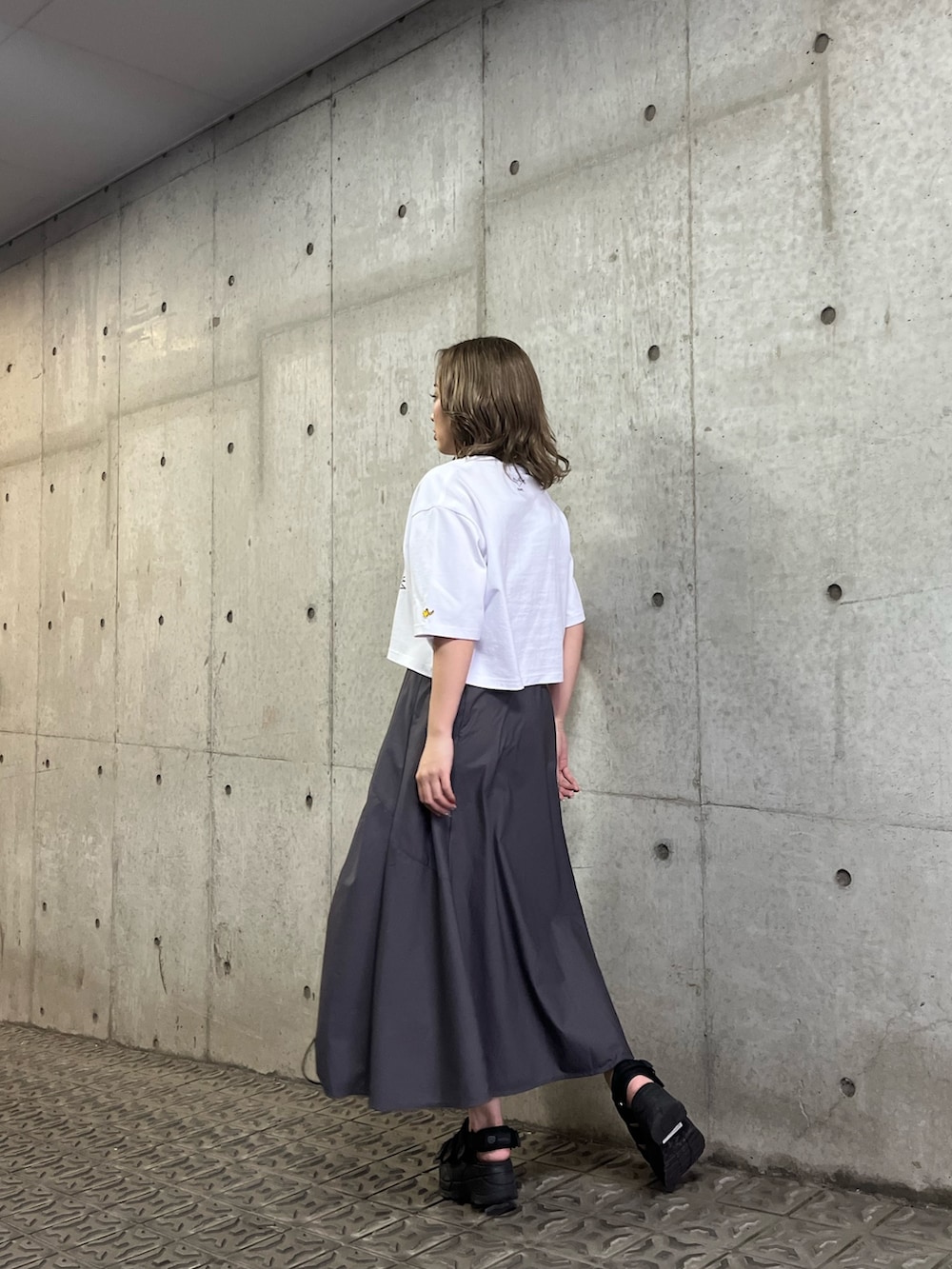 ブラック系のサンダル、ホワイト系のTシャツ/カットソー、グレー系のスカートを着用したレディースの春コーディネートの2枚目の写真