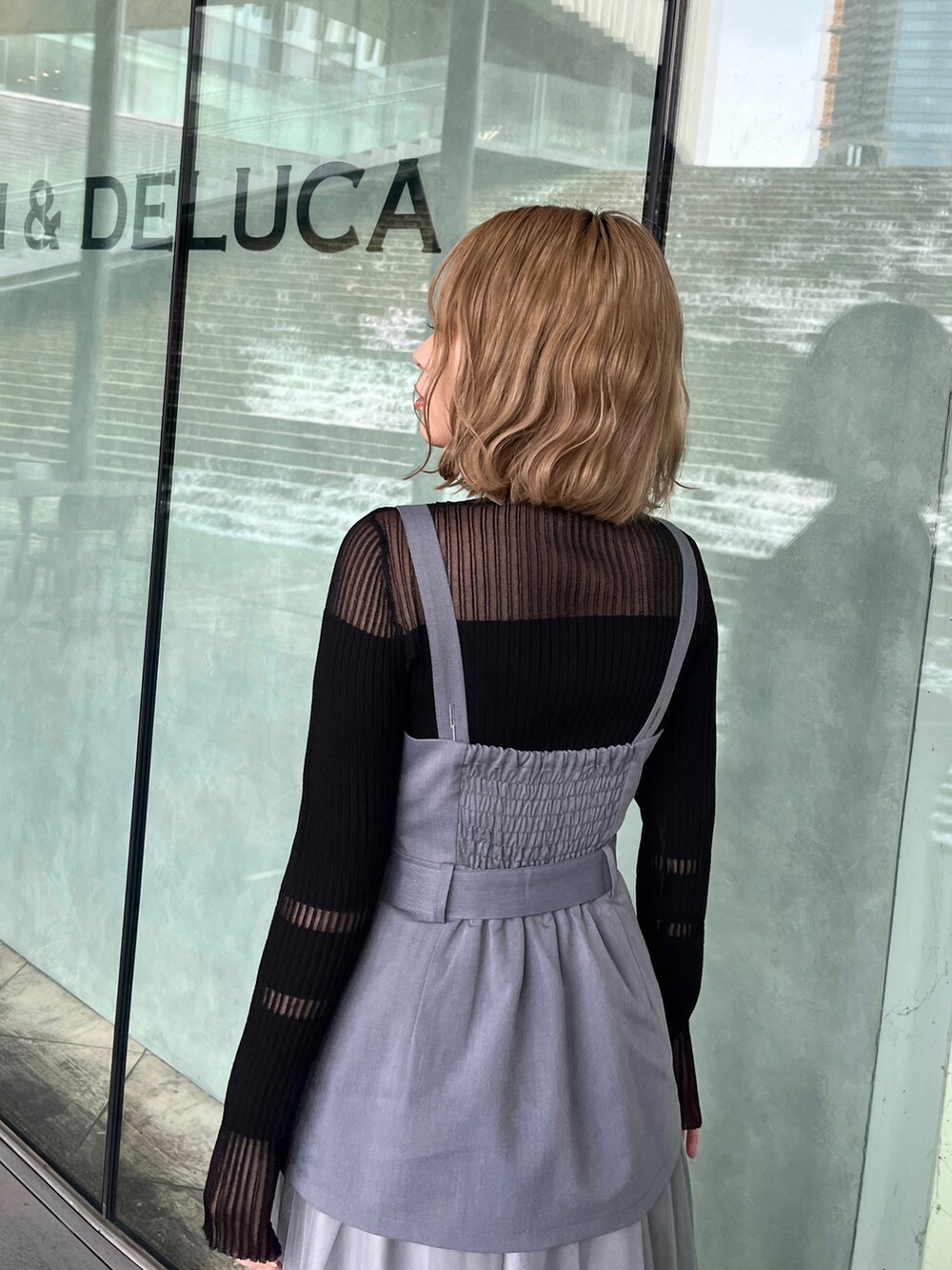 ブラック系のニット/セーター、グレー系のジャンパースカート、ブラック系のブーツを着用したレディースの春コーディネートの5枚目の写真