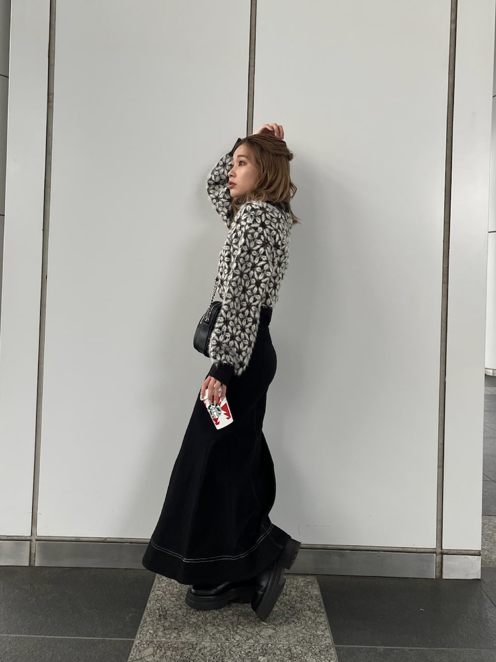 ブラック系のニット/セーター、ブラック系のスカート、ブラック系のショルダーバッグを着用したレディースの秋コーディネートの2枚目の写真