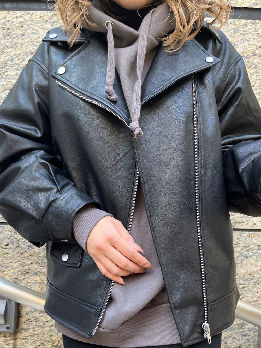 ブラック系のライダースジャケット、グレー系のパーカー、ブラック系のブーツを着用したレディースの秋コーディネートの9枚目の写真