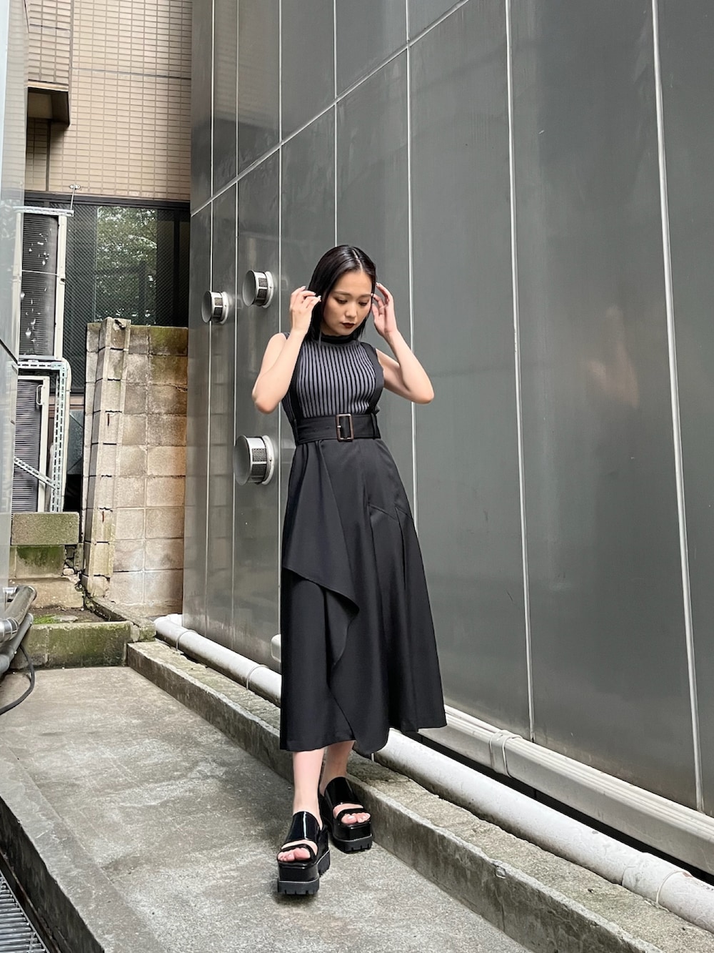 ブラック系のジャンパースカート、ブラック系のニット/セーター、ブラック系のサンダルを着用したレディースの夏コーディネートの3枚目の写真