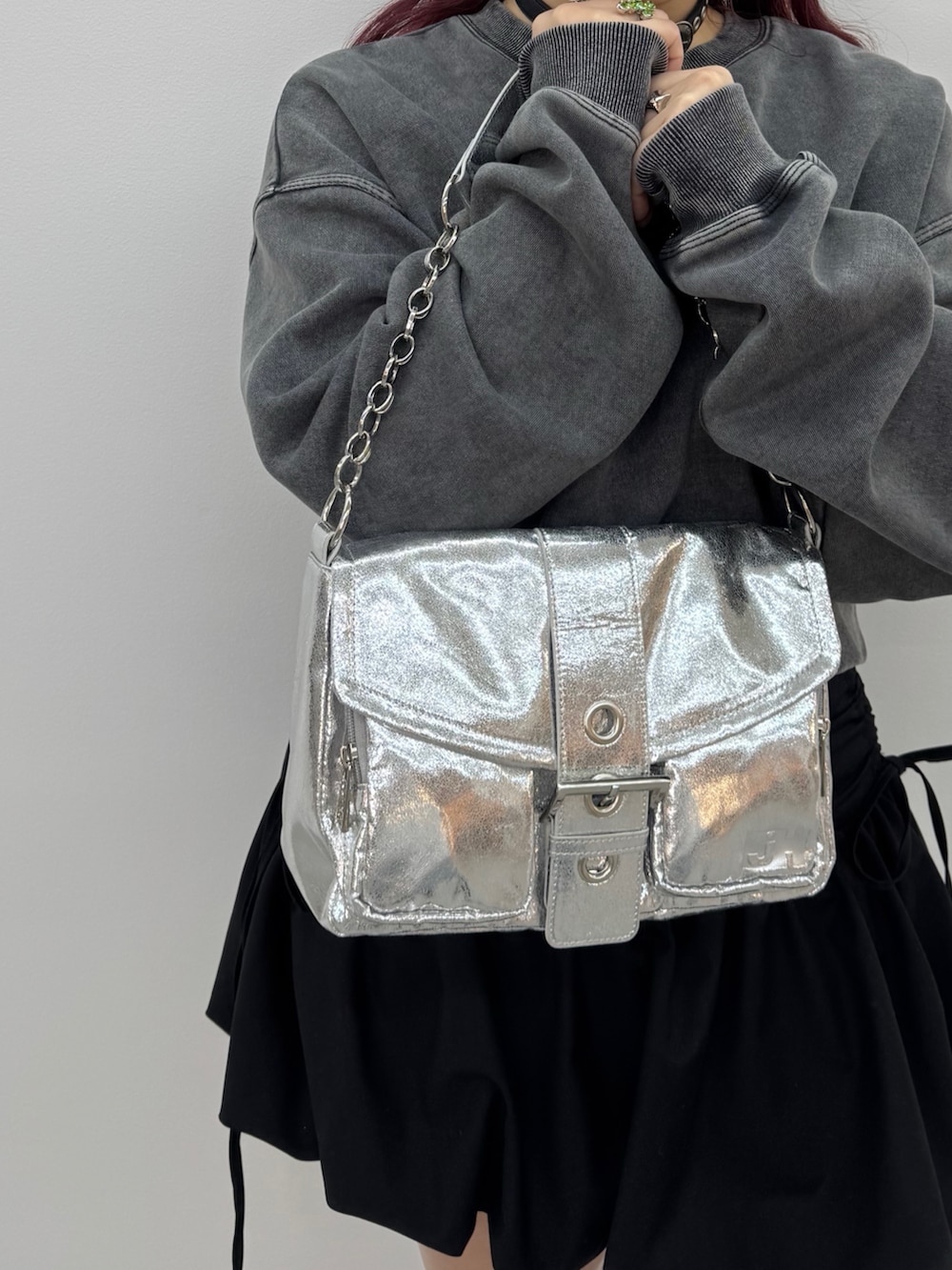 シルバー系のハンドバッグ、ブラック系のスウェットを着用したレディースの冬コーディネートの3枚目の写真