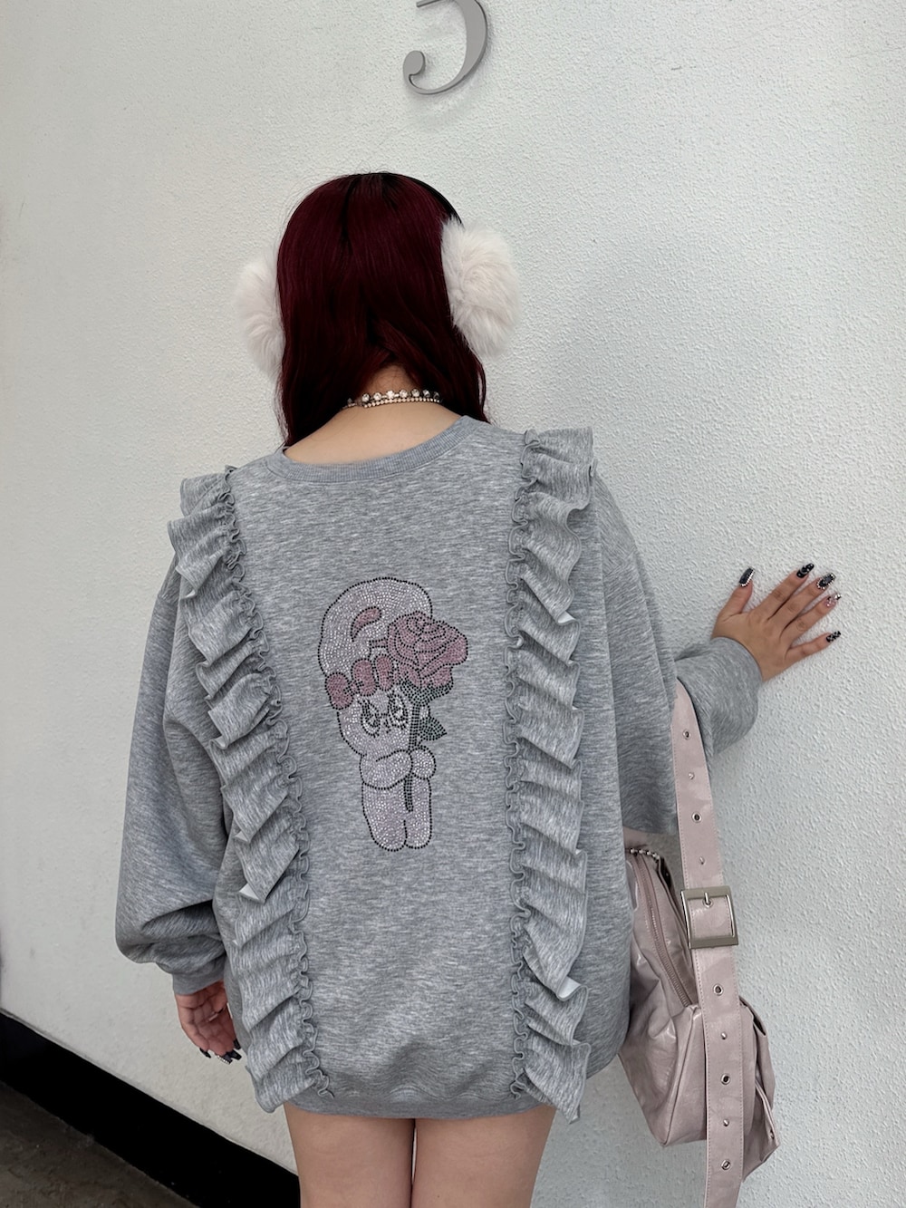 グレー系のスウェット、ピンク系のショルダーバッグ、ホワイト系のイヤーマフを着用したレディースの秋コーディネートの3枚目の写真