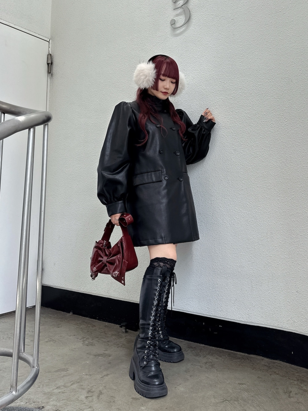 ブラック系のその他アウター、レッド系のショルダーバッグ、ホワイト系のイヤーマフを着用したレディースの秋コーディネートの2枚目の写真