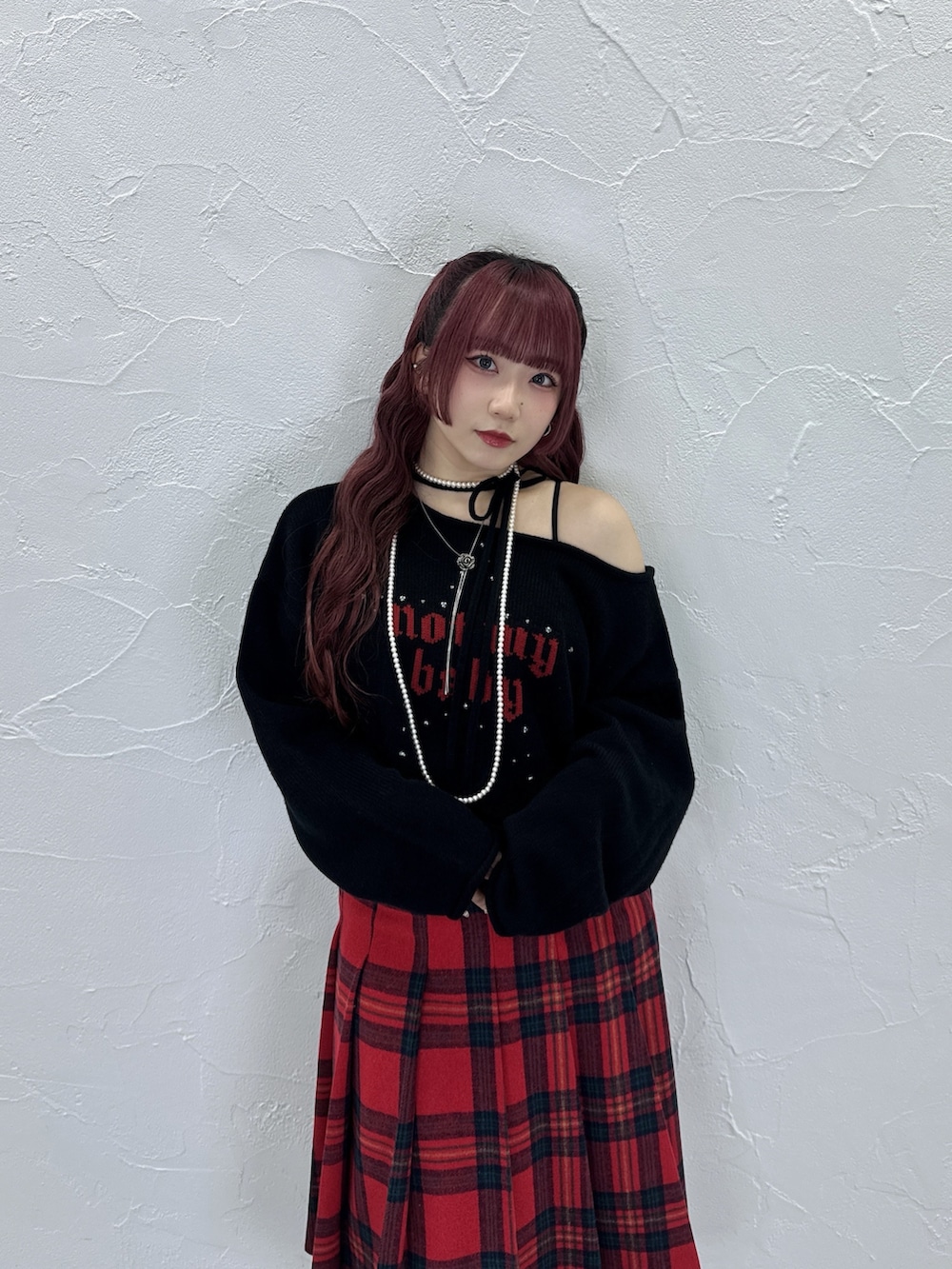 ブラック系のニット/セーター、レッド系のスカートを着用したレディースの秋コーディネートの3枚目の写真