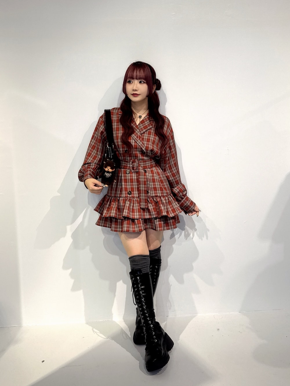 レッド系のワンピース、ブラック系のハンドバッグ、ブラウン系のキーホルダーを着用したレディースの秋コーディネートの2枚目の写真