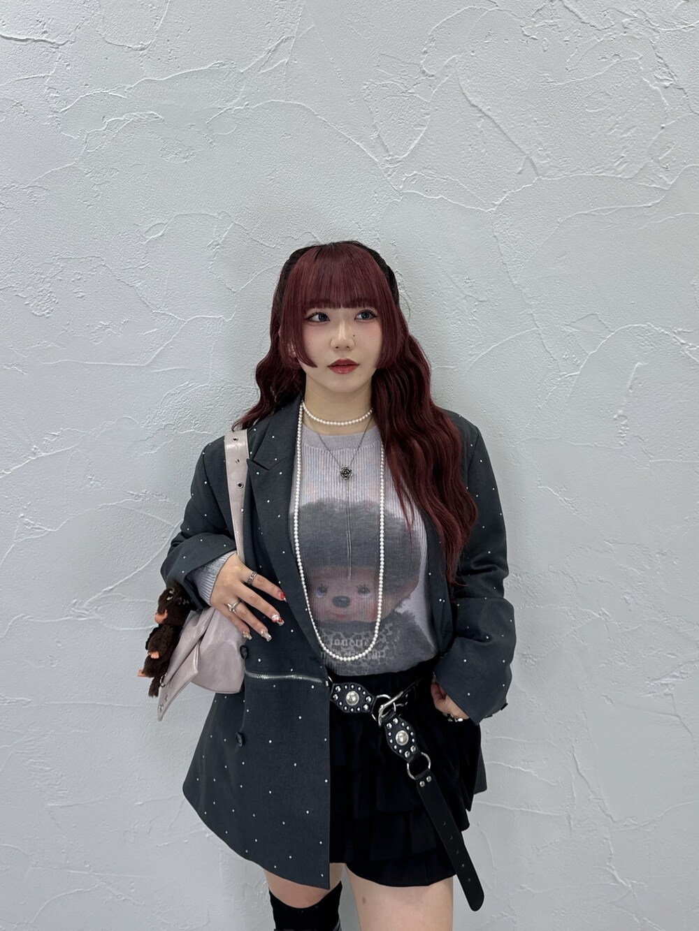 ピンク系のニット/セーター、グレー系のテーラードジャケット、ピンク系のショルダーバッグを着用したレディースの夏コーディネートの2枚目の写真