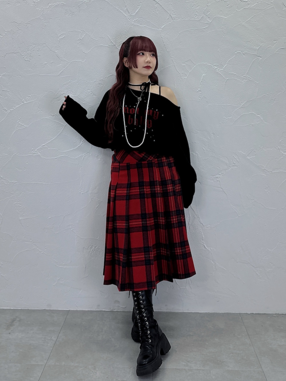 ブラック系のニット/セーター、レッド系のスカートを着用したレディースの秋コーディネートの2枚目の写真