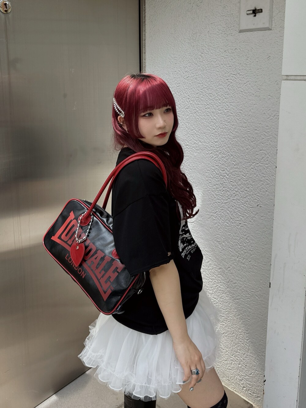 ブラック系のボストンバッグ、ホワイト系のスカート、ブラック系のブーツを着用したレディースの春コーディネートの2枚目の写真