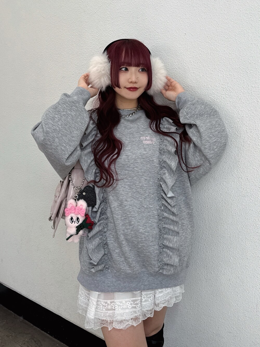 グレー系のスウェット、ピンク系のショルダーバッグ、ホワイト系のイヤーマフを着用したレディースの秋コーディネートの2枚目の写真