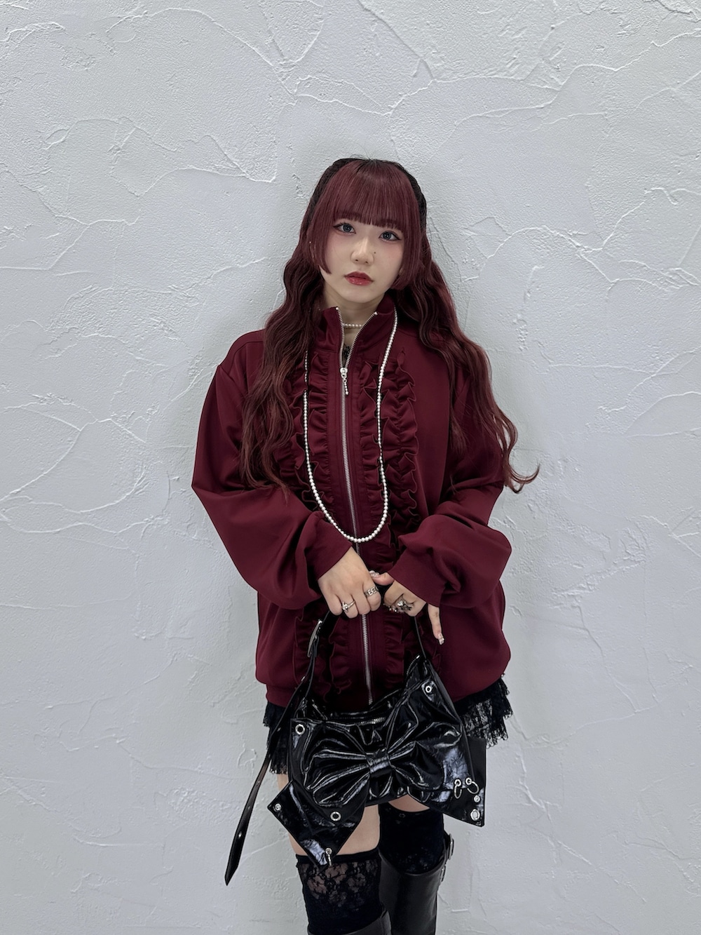 レッド系のジャージ、ブラック系のショルダーバッグ、ブラック系のブーツを着用したレディースの秋コーディネートの3枚目の写真