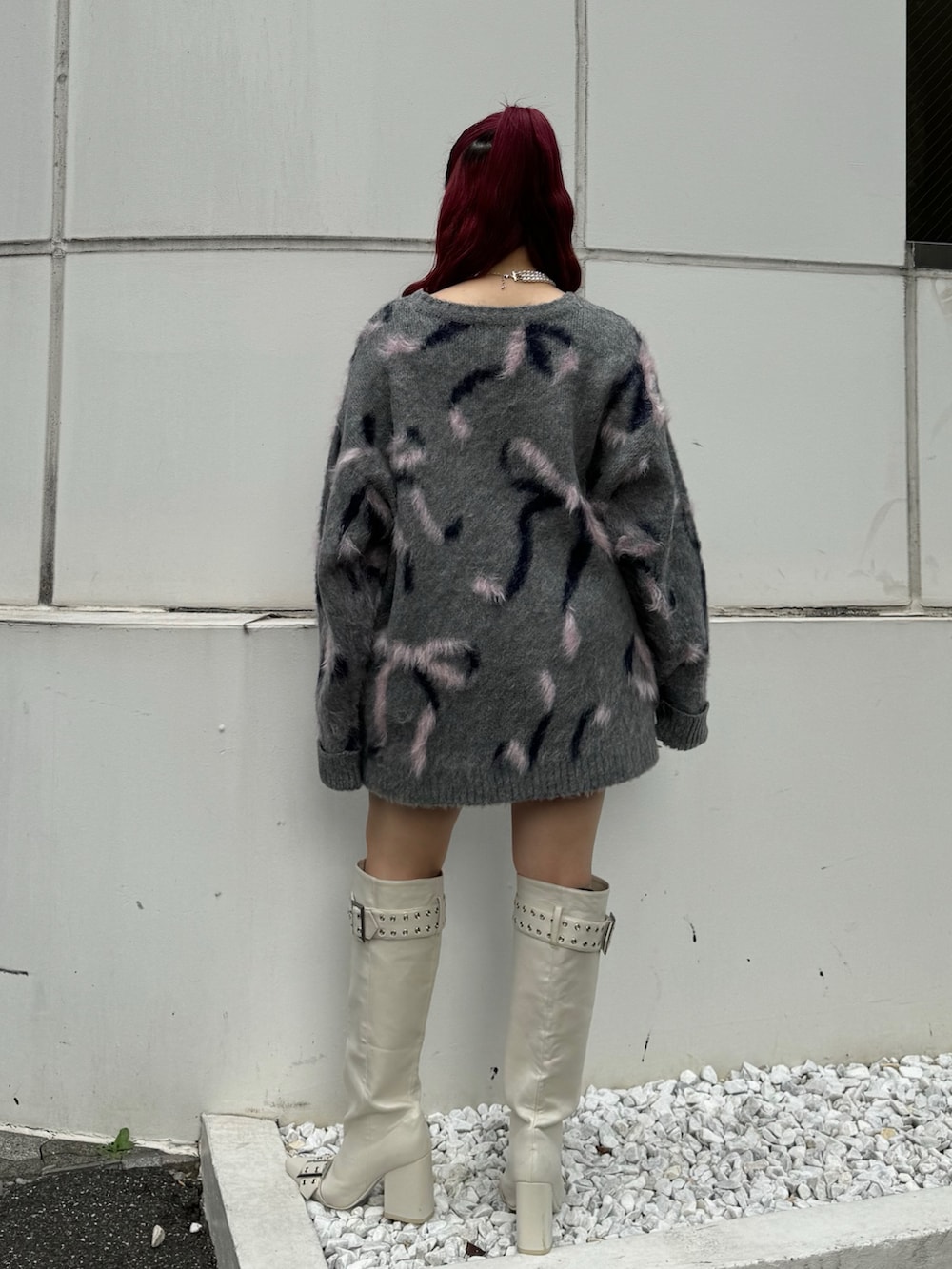 グレー系のニット/セーター、ピンク系のスカート、ホワイト系のブーツを着用したレディースの秋コーディネートの3枚目の写真