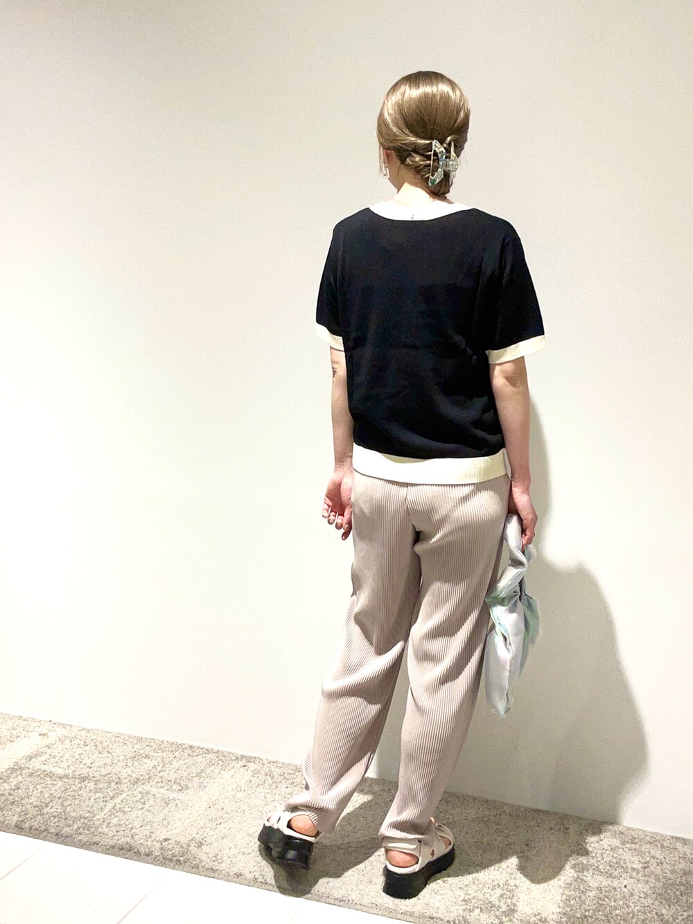 ブラック系のニット/セーター、グレー系のその他パンツ、シルバー系のハンドバッグを着用したレディースの春コーディネートの3枚目の写真