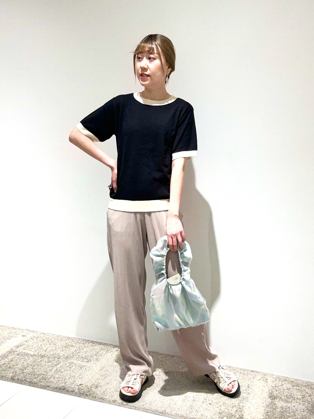 ブラック系のニット/セーター、グレー系のその他パンツ、シルバー系のハンドバッグを着用したレディースの春コーディネートの2枚目の写真