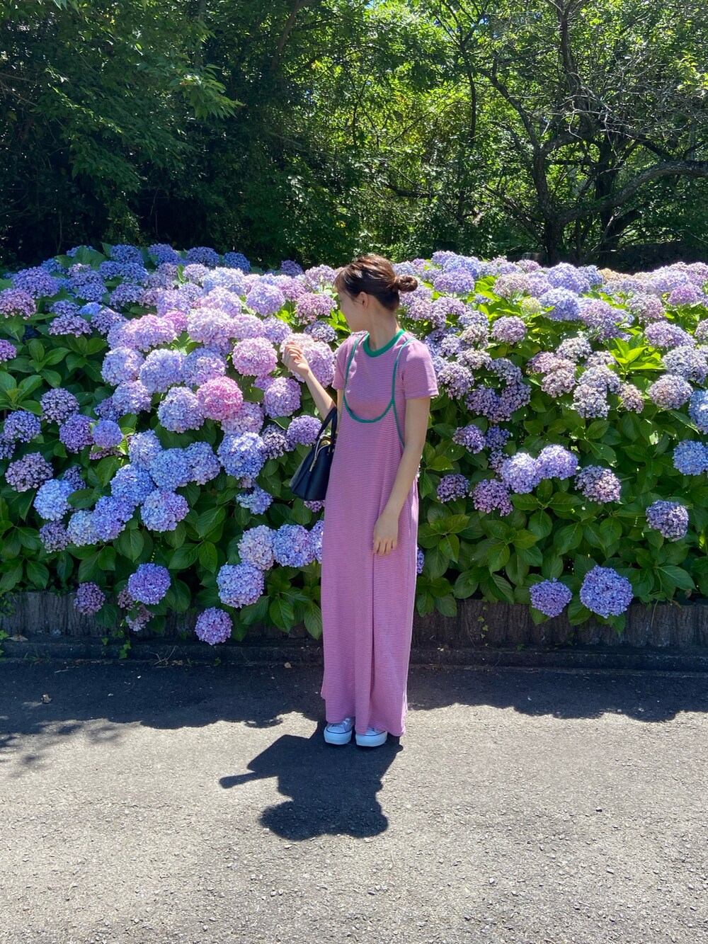 ピンク系のワンピース、ブラック系のバッグ、シルバー系のスニーカーを着用したレディースの夏コーディネートの2枚目の写真