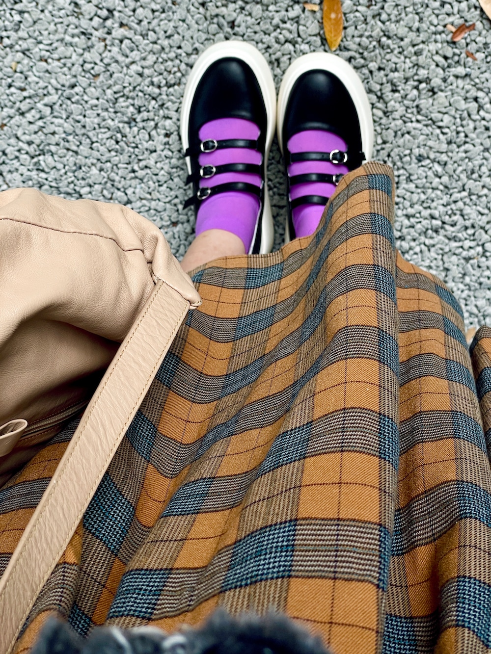 ベージュ系のバックパック/リュック、ブラック系のシューズ、オレンジ系のスカートを着用したレディースの秋コーディネートの3枚目の写真