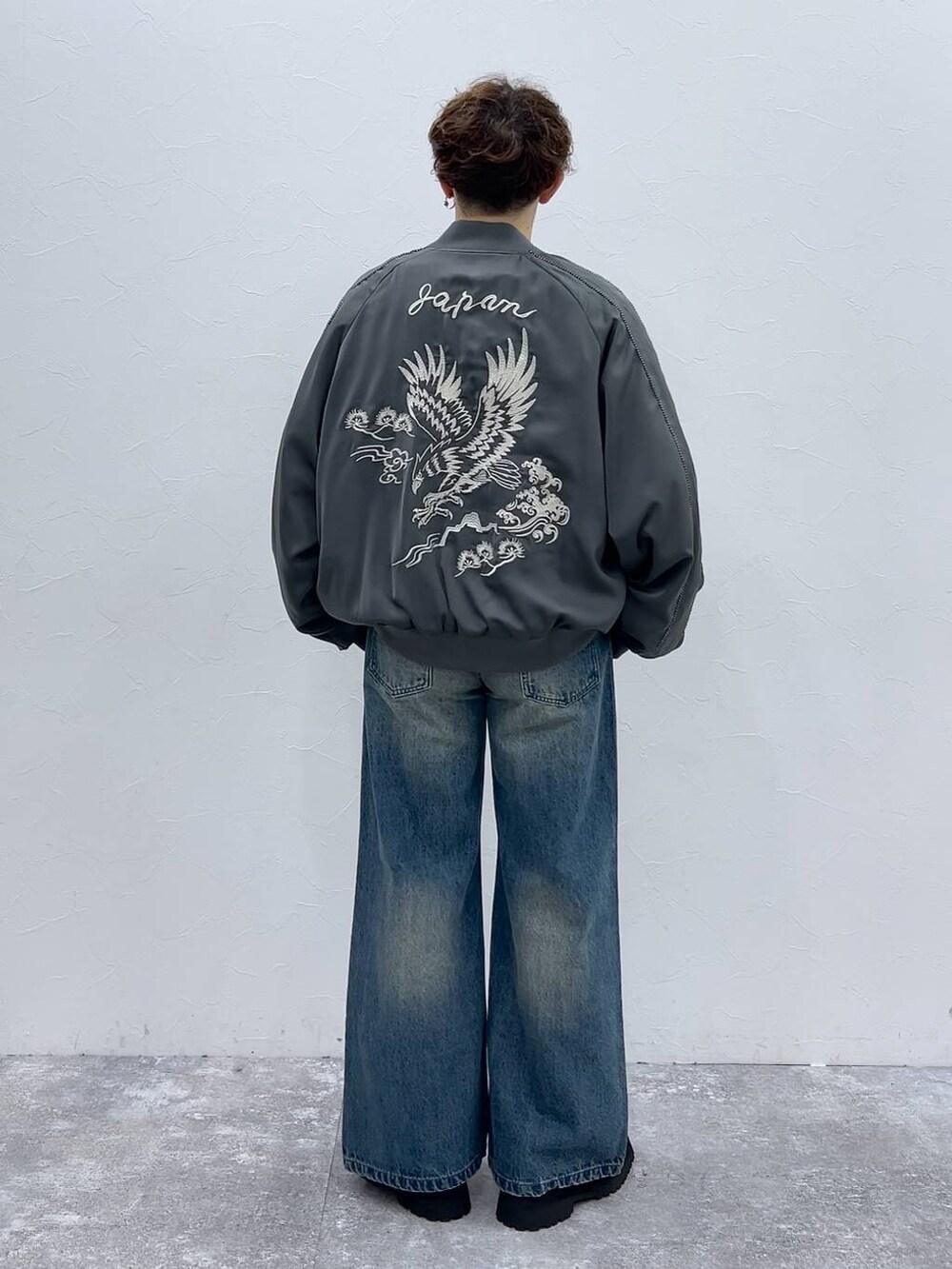 ブルー系のデニムパンツ、ブラック系のドレスシューズ、グレー系のスカジャンを着用したメンズの秋コーディネートの3枚目の写真