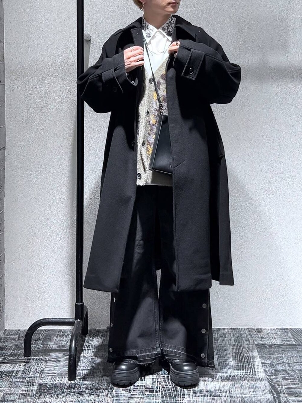 ブラック系のステンカラーコート、ブラック系のショルダーバッグ、グレー系のカーディガン/ボレロを着用したメンズの冬コーディネートの2枚目の写真