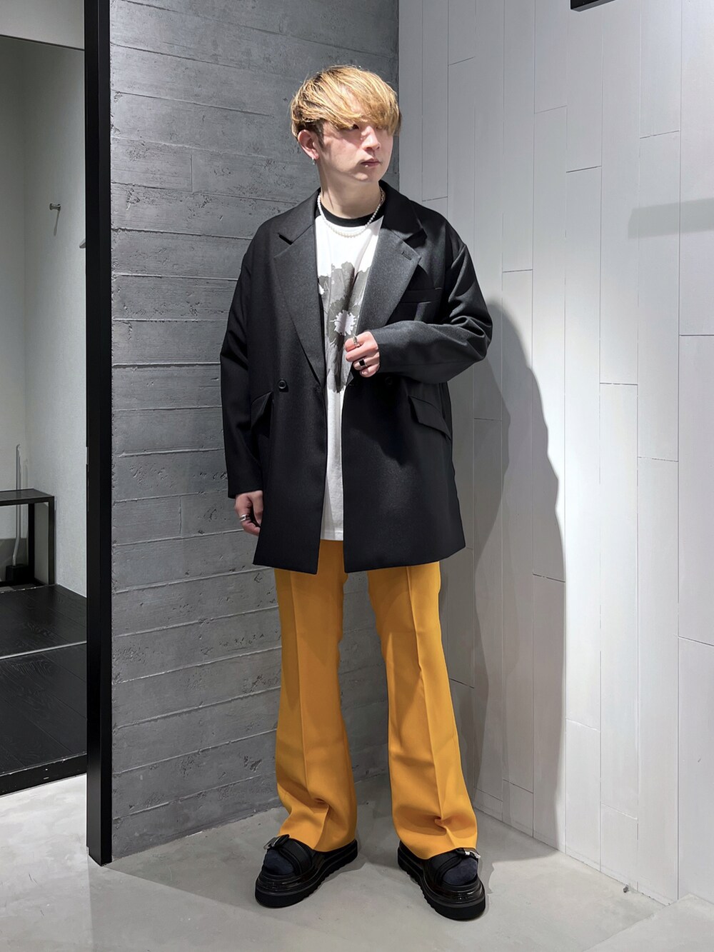 ブラック系のTシャツ/カットソー、ブラック系のテーラードジャケット、イエロー系のスラックスを着用したメンズの春コーディネートの3枚目の写真