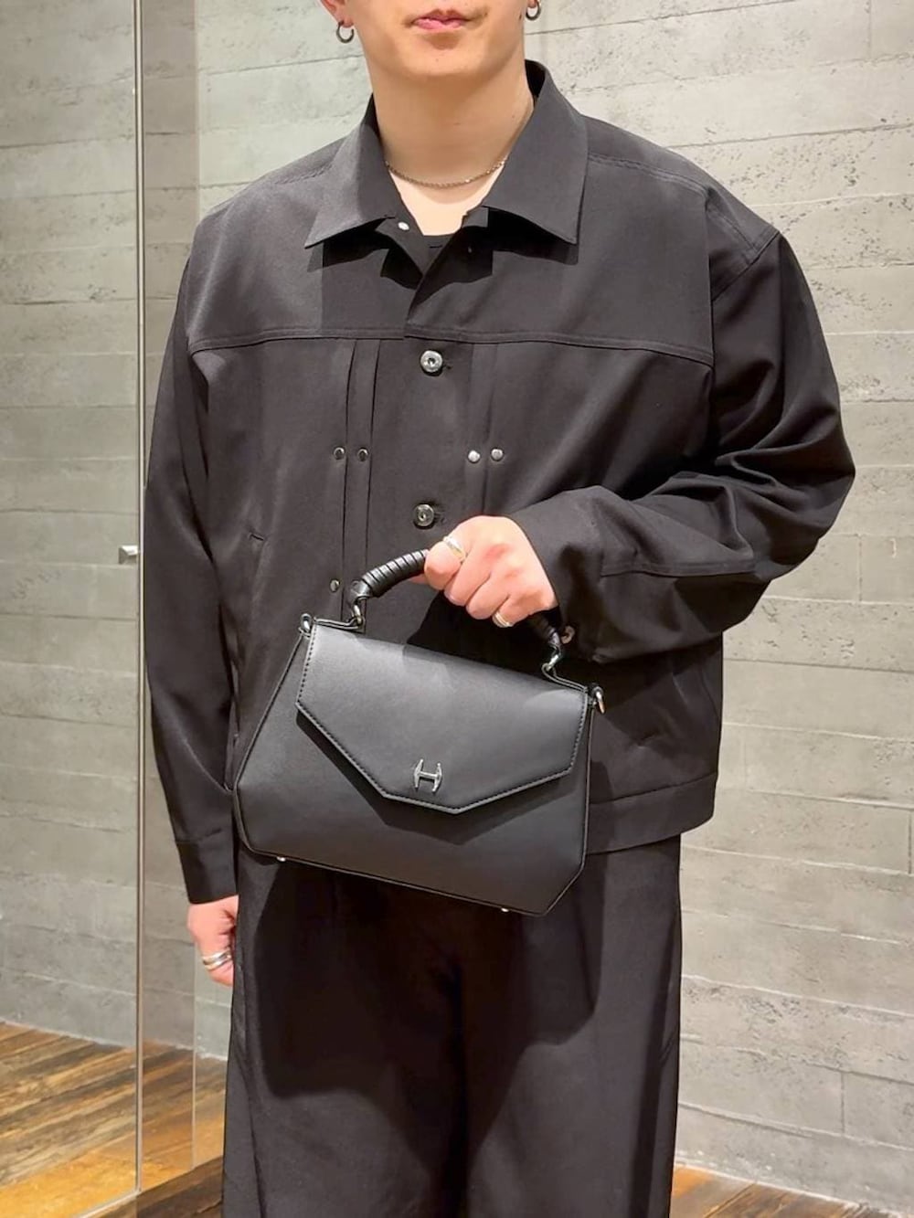 ブラック系のスラックス、ブラック系のブルゾン、ブラック系のショルダーバッグを着用したメンズの春コーディネートの5枚目の写真