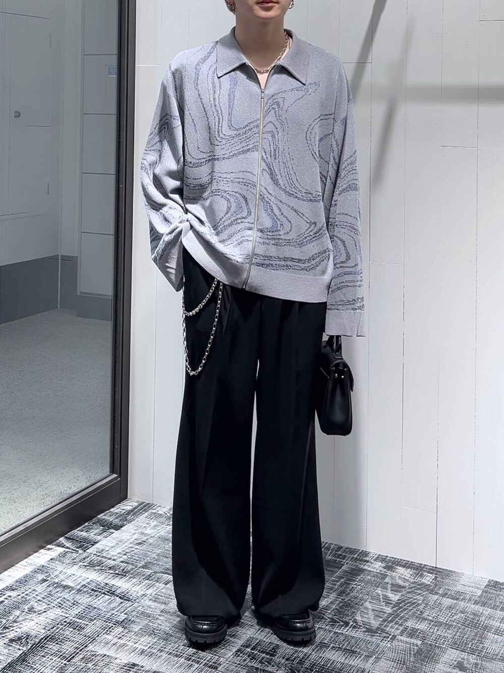 ブラック系のスラックス、グレー系のカーディガン/ボレロ、ブラック系のドレスシューズを着用したメンズの春コーディネートの2枚目の写真