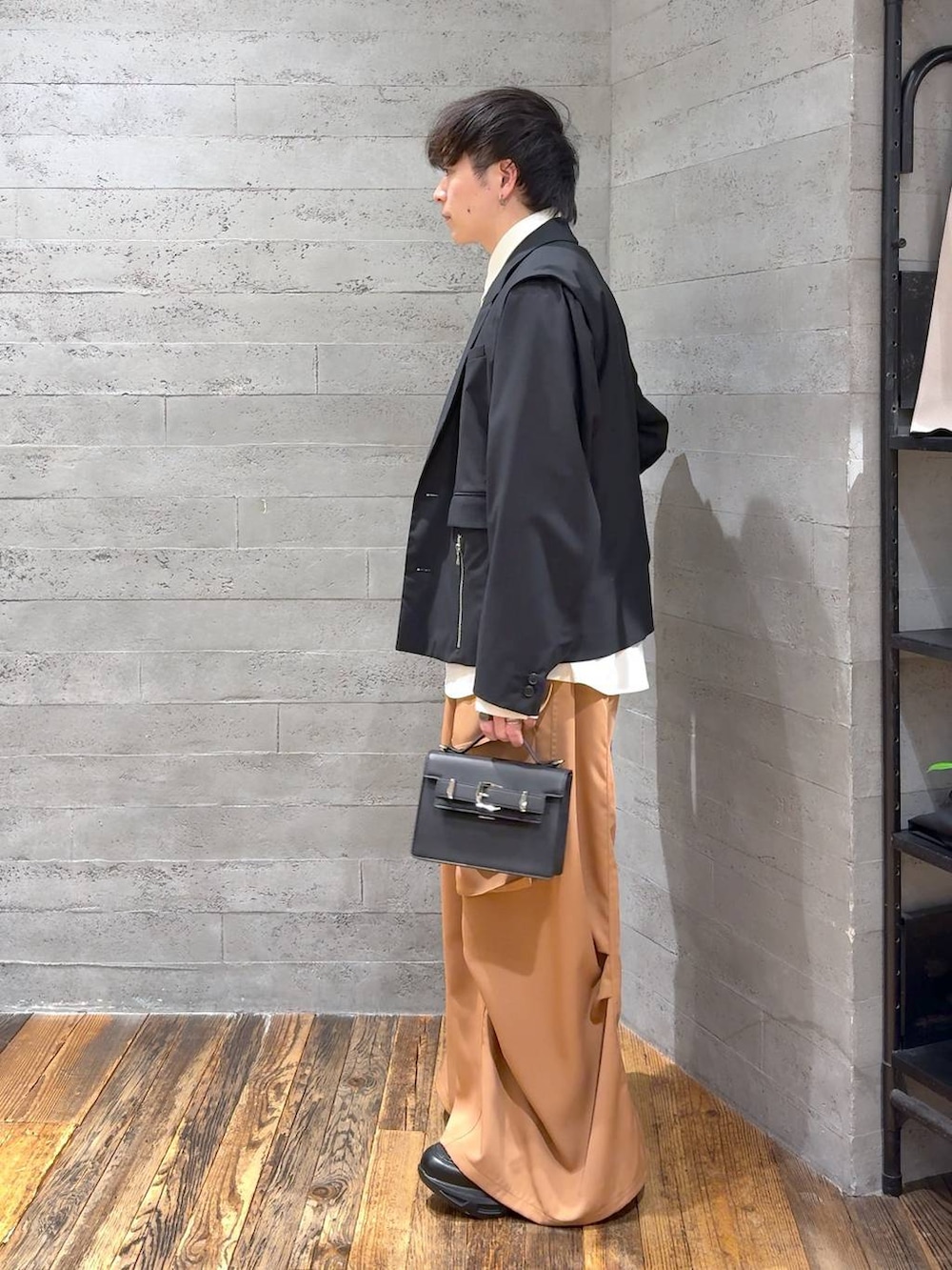 ブラック系のスニーカー、ブラック系のハンドバッグ、ブラック系のテーラードジャケットを着用したメンズの冬コーディネートの4枚目の写真